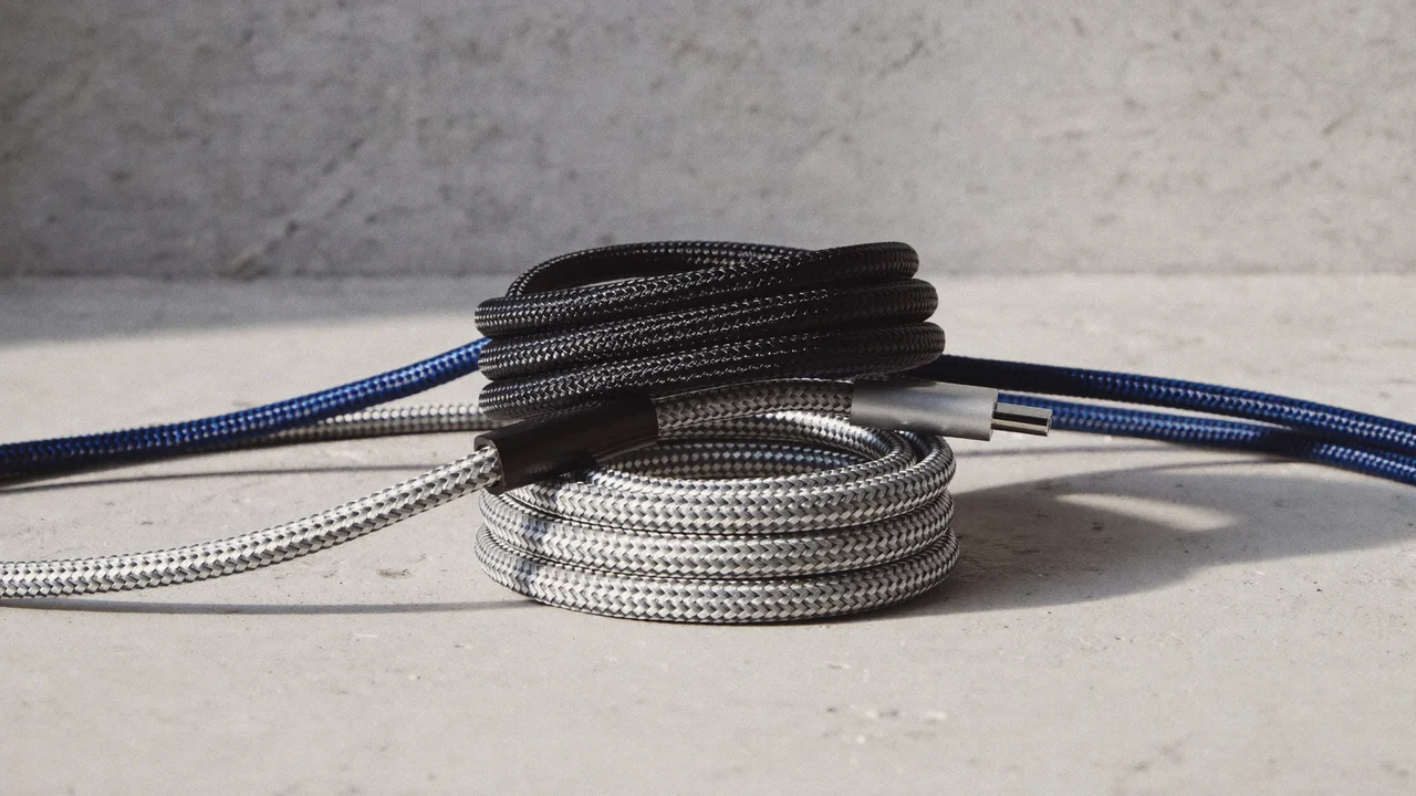 Tre flettede USB-C-kabler i forskellige farver, rullet løst på beton